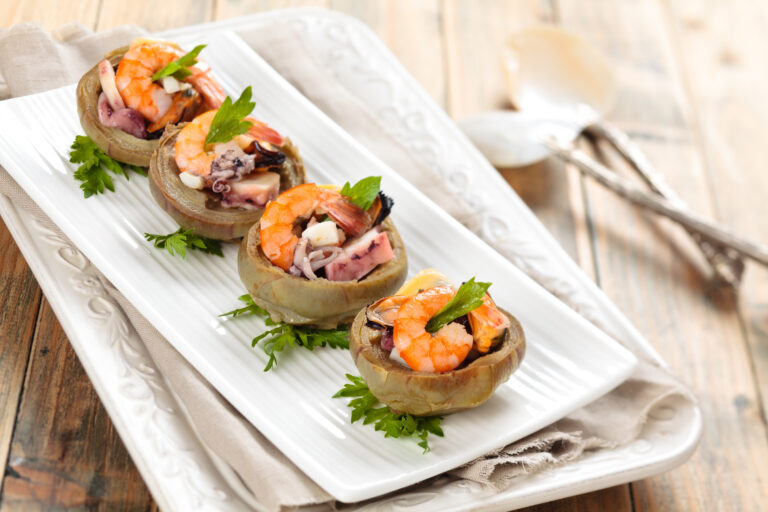 Artichoke bottoms filled with shrimp and herbs, plated as an appetiser