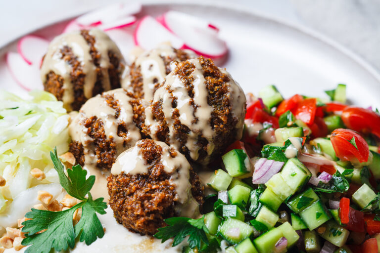 Falafel drizzled with tahini, served with a chopped cucumber and tomato salad