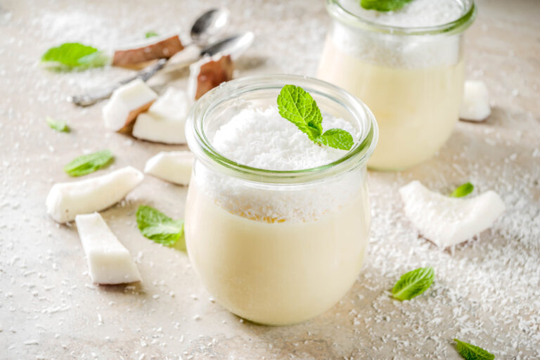 Coconut milk desserts set in glass jars, with fresh coconut alongside