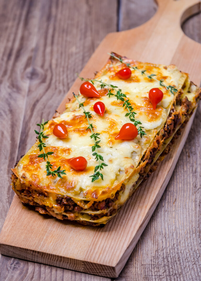 Lasagne topped with melted cheese, cherry tomatoes and thyme
