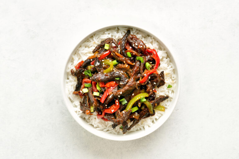 Crispy chilli beef with sliced red and green peppers over rice