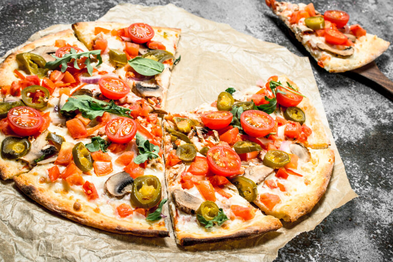 Pizza topped with sliced jalapenos, cherry tomatoes and basil