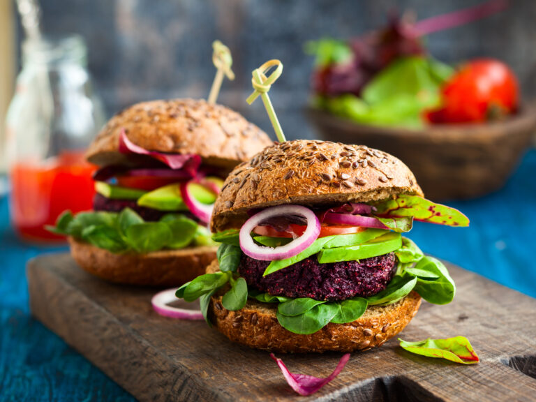 Quinoa and beetroot burgers on seeded buns with salad leaves and red onion