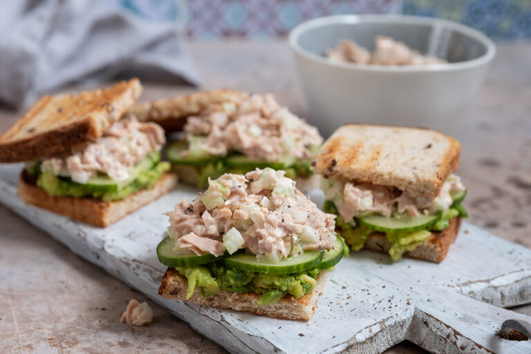 Tuna sandwiches with avocado and cucumber on a board
