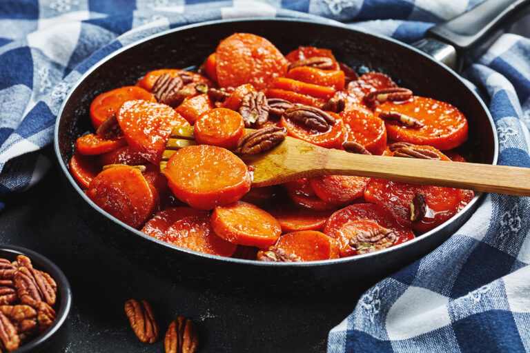 Candied sweet potatoes with pecans in a cast-iron skillet